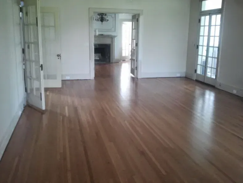 An empty living room with hardwood floors and white walls