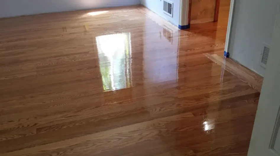 A room with a wooden floor and a door leading to a hallway.