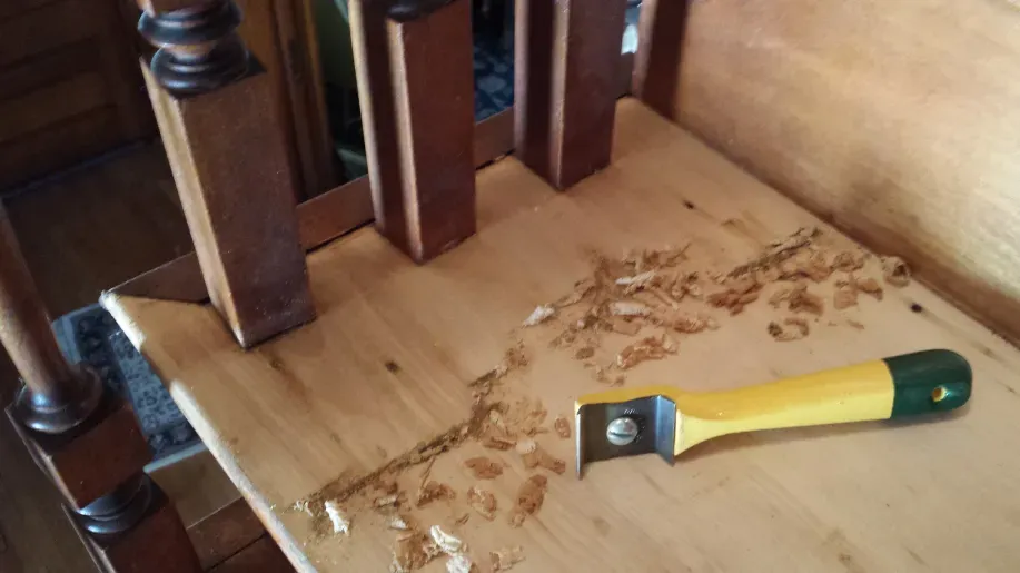 A yellow and green tool is sitting on top of a wooden table.