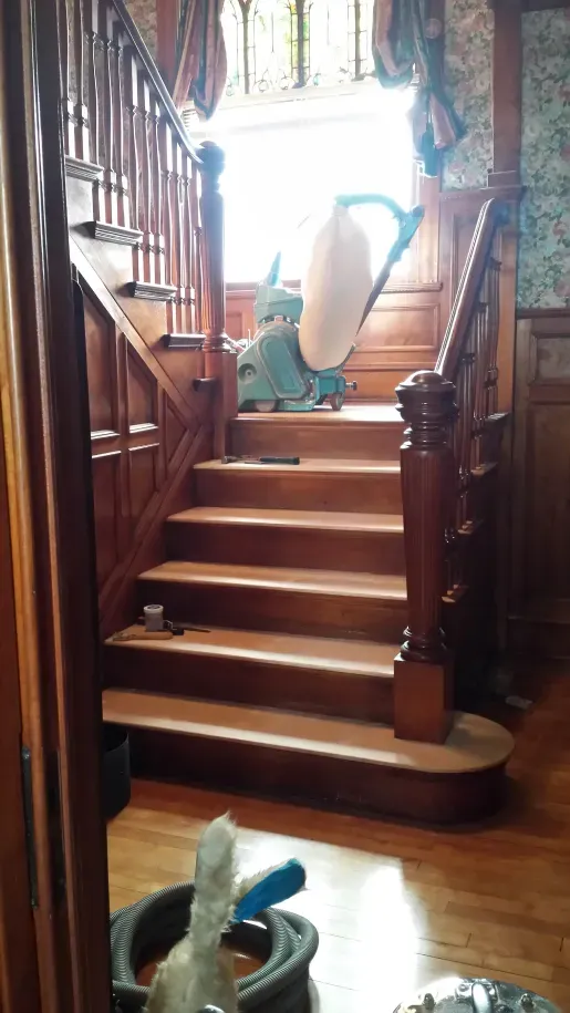 A vacuum cleaner is sitting on top of a wooden staircase.