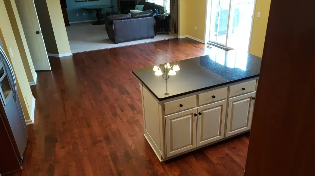 A kitchen with hardwood floors and a large island in the middle of the room.