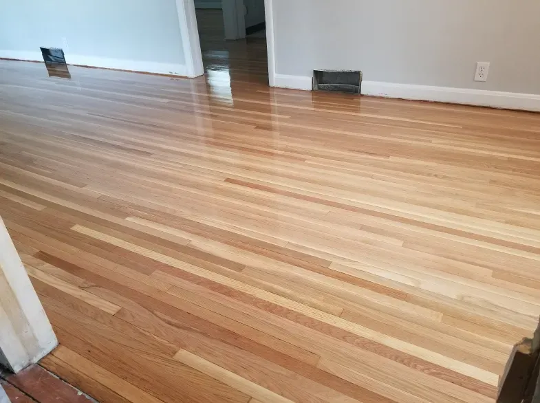 A living room with hardwood floors and a doorway leading to a hallway.