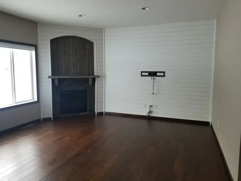 An empty living room with hardwood floors and a fireplace.