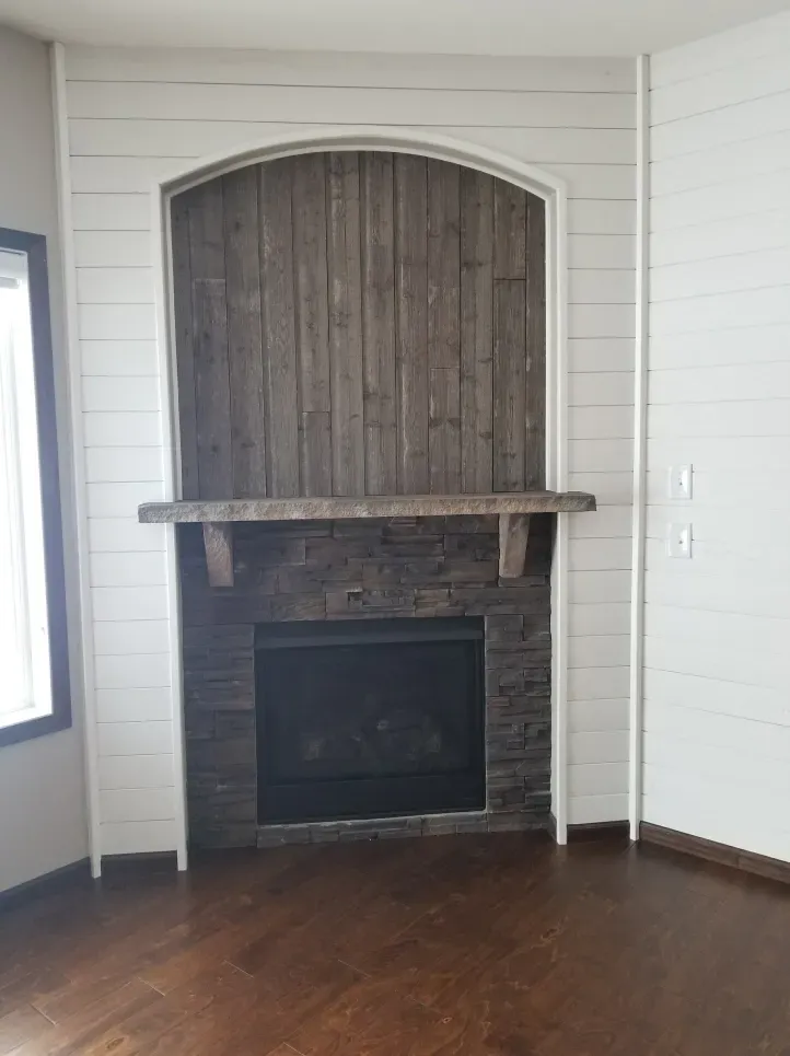 An empty living room with a fireplace and a wooden mantle