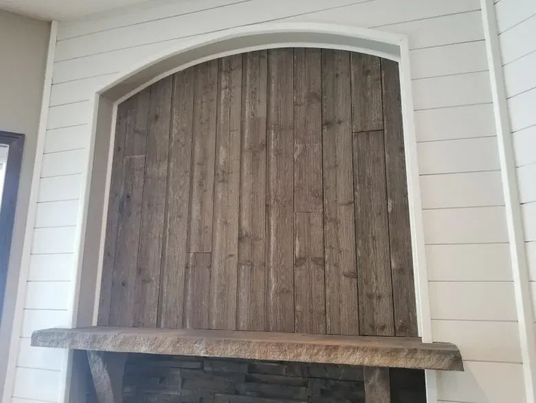 A fireplace with a wooden mantle and a wooden wall behind it.