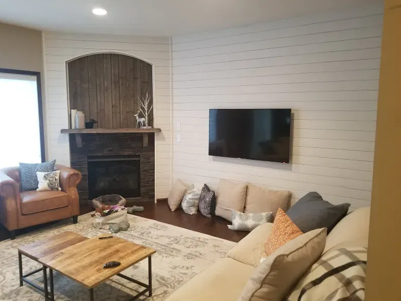 A living room with a couch , chair , coffee table and television.