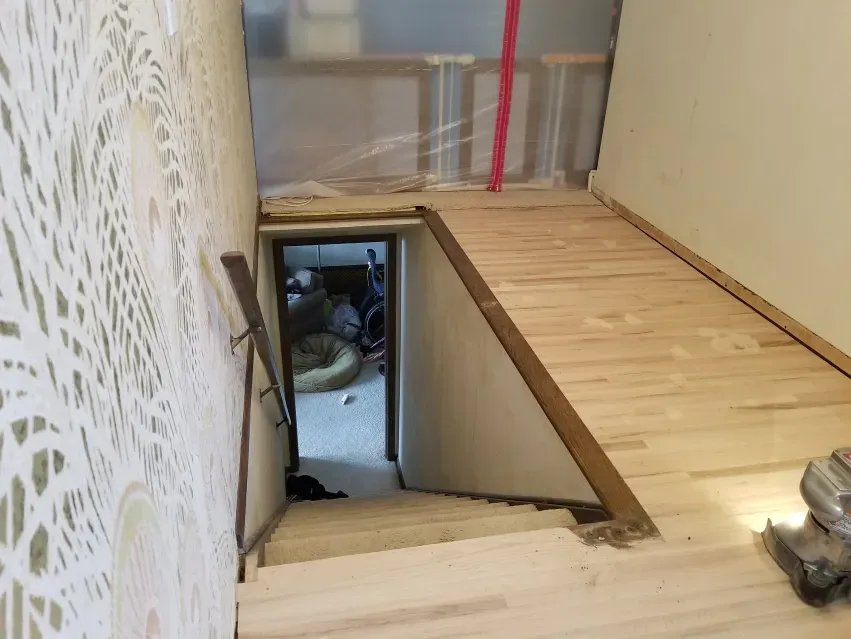 A wooden staircase leading to a basement under construction.