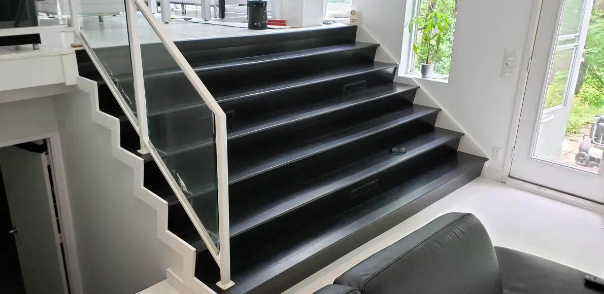 A black staircase with a white railing in a living room next to a couch.