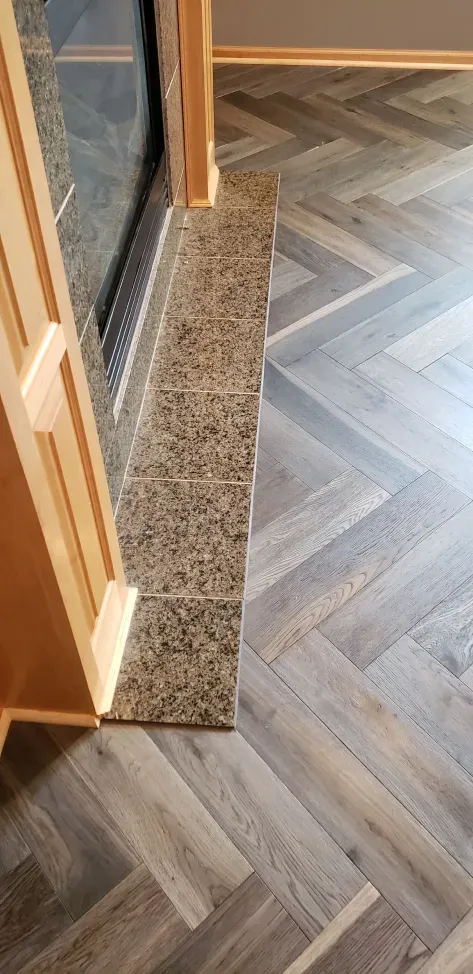 There is a fireplace in the background and a herringbone floor in the foreground.