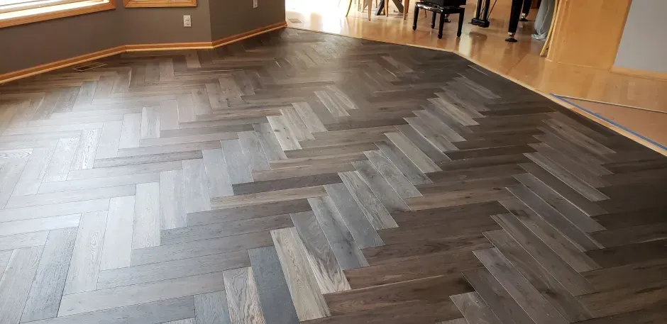 A wooden floor with a herringbone pattern in a room.