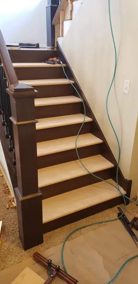 A wooden staircase with white steps is being built in a house.