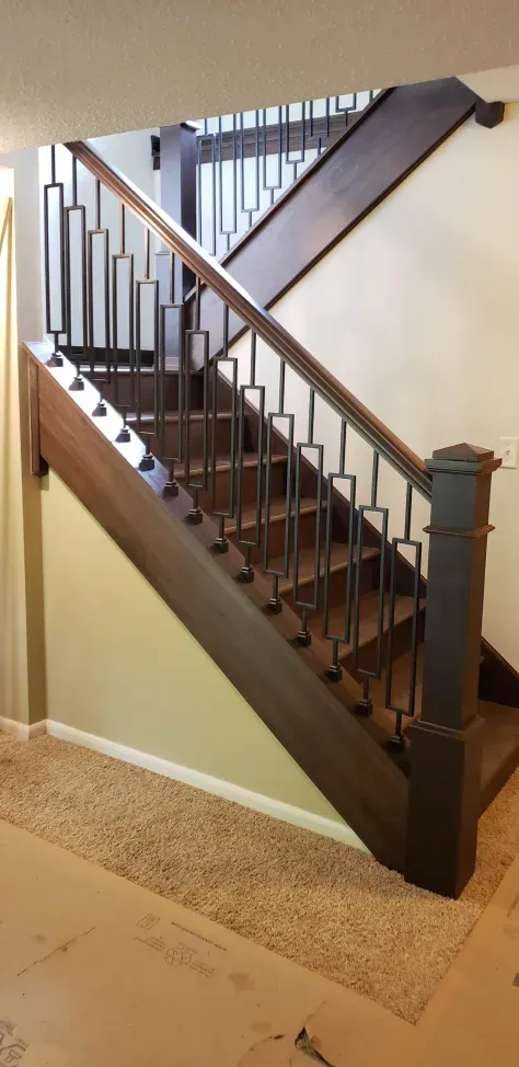 A wooden staircase with a metal railing in a room.