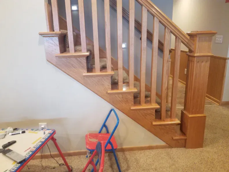 A wooden staircase with a red and blue chair underneath it