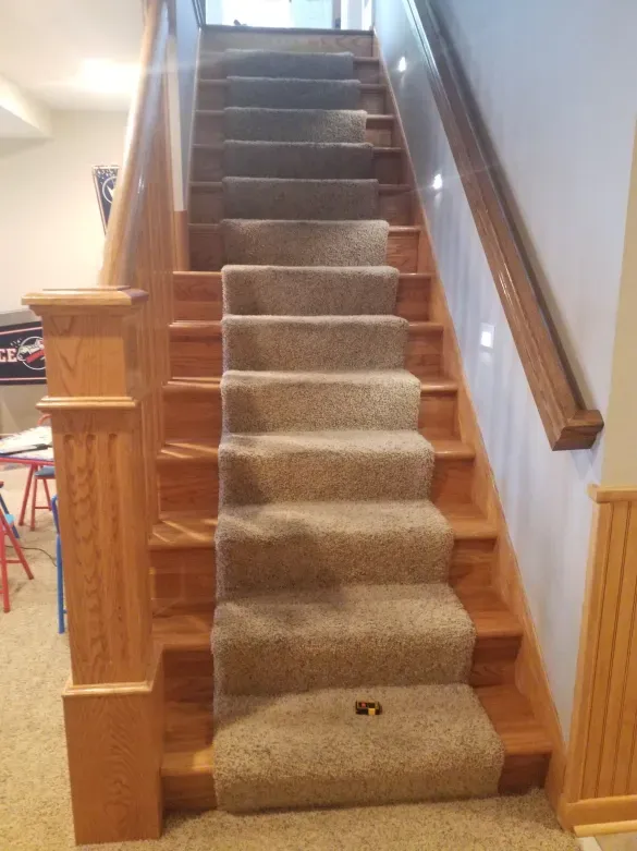 A wooden staircase with a carpeted staircase and a wooden railing.