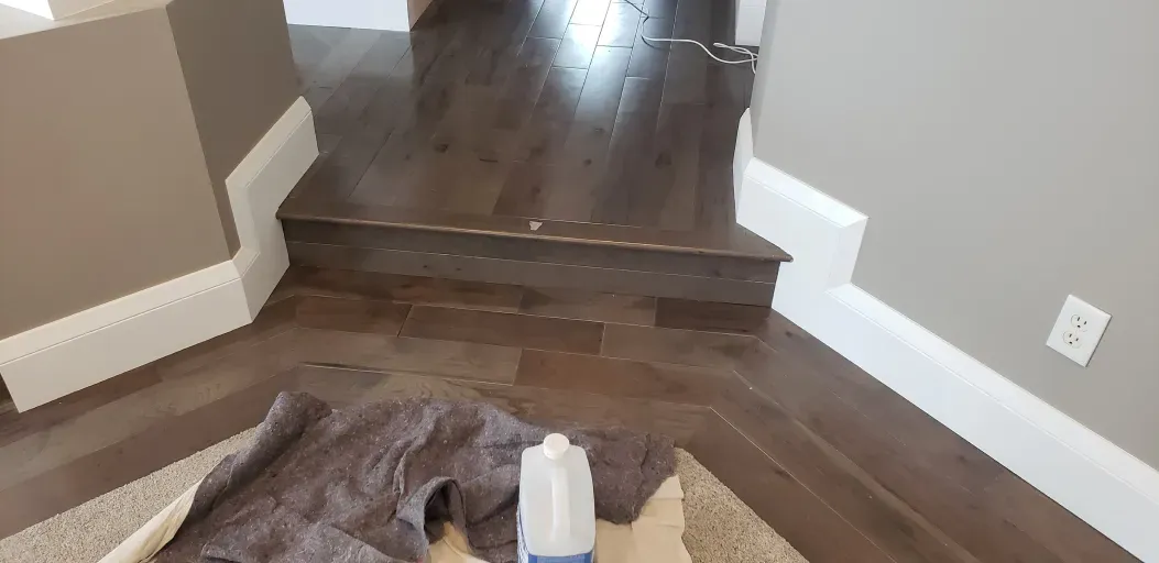 A gallon of milk is sitting on the floor next to a box.