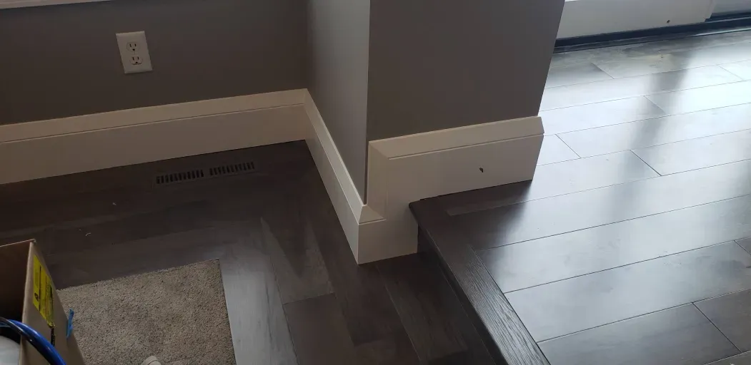 A room with a wooden floor and a white trim on the wall.