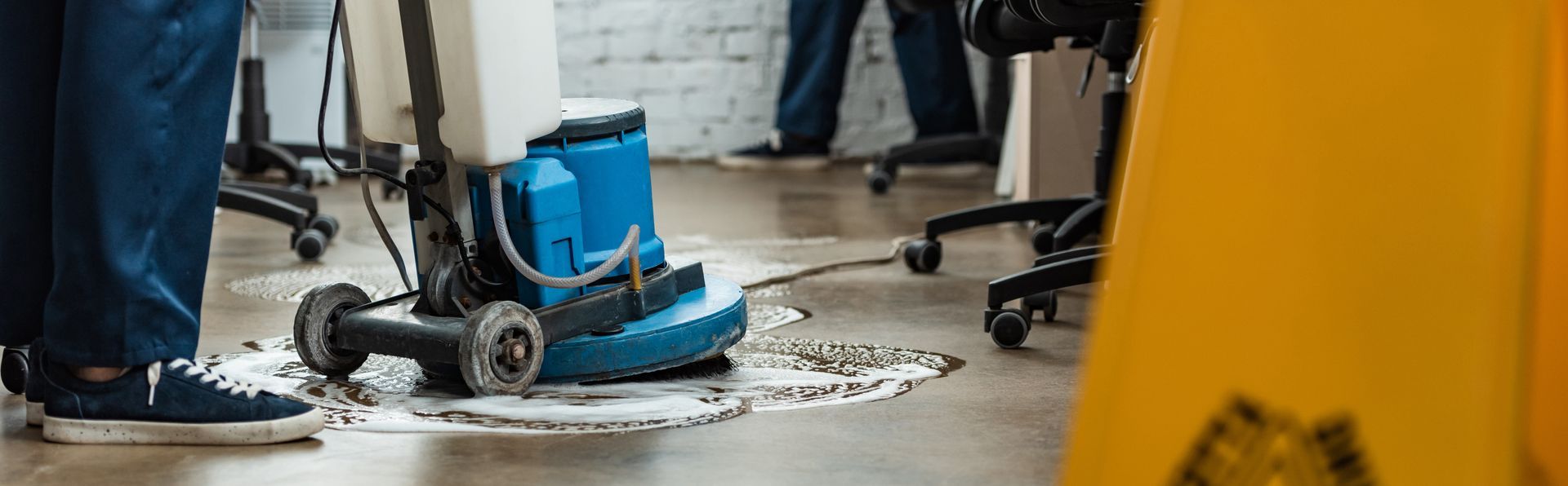 A person is cleaning a wet floor with a vacuum cleaner.