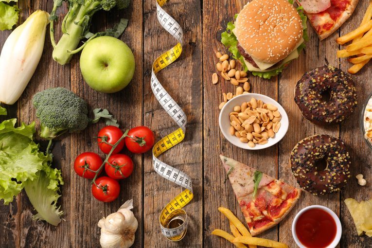 Food on a wooden table with a tape measure dividing the healthy from unhealthy food