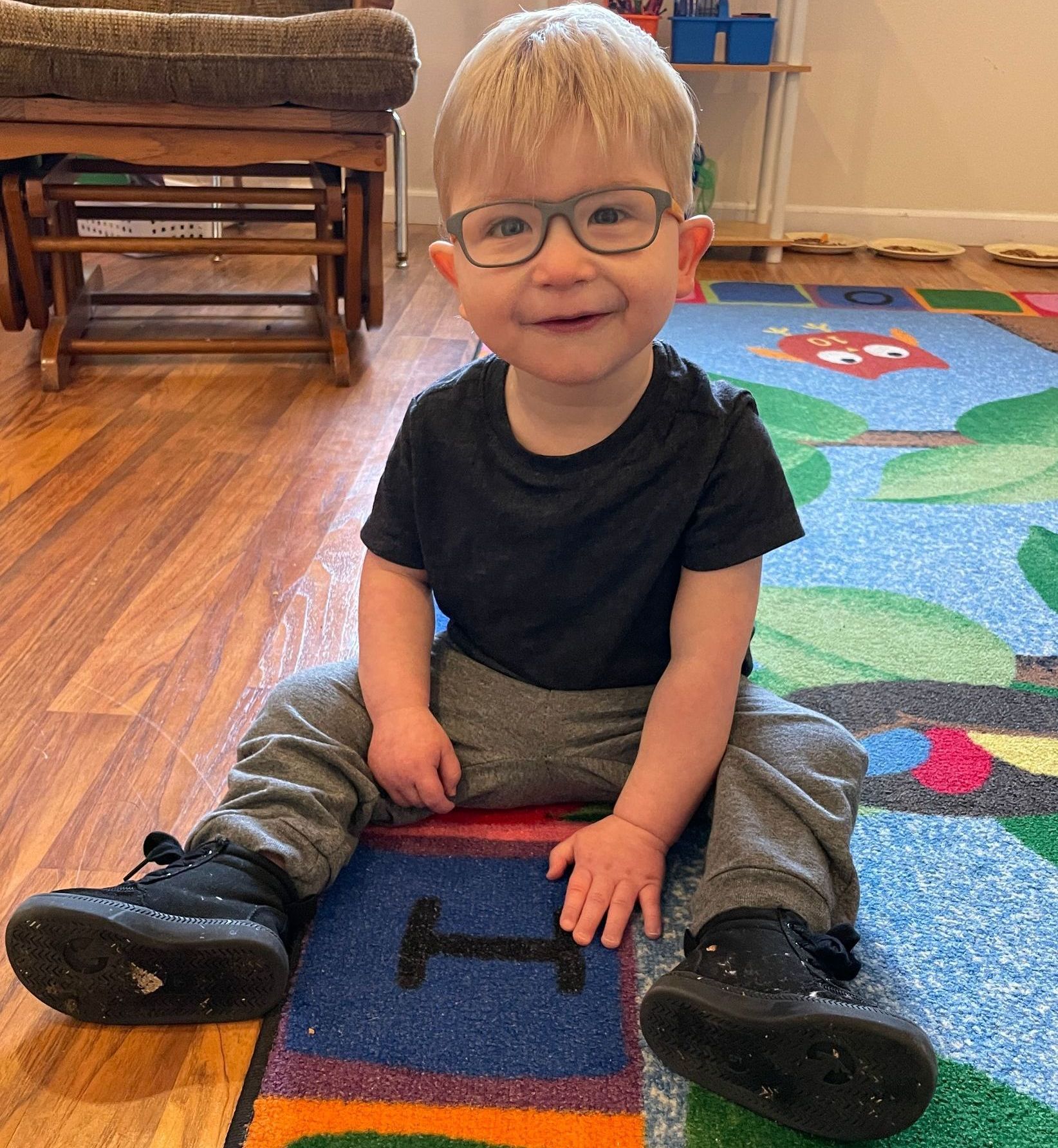 young child sitting on the floor with a speech therapy, practicing