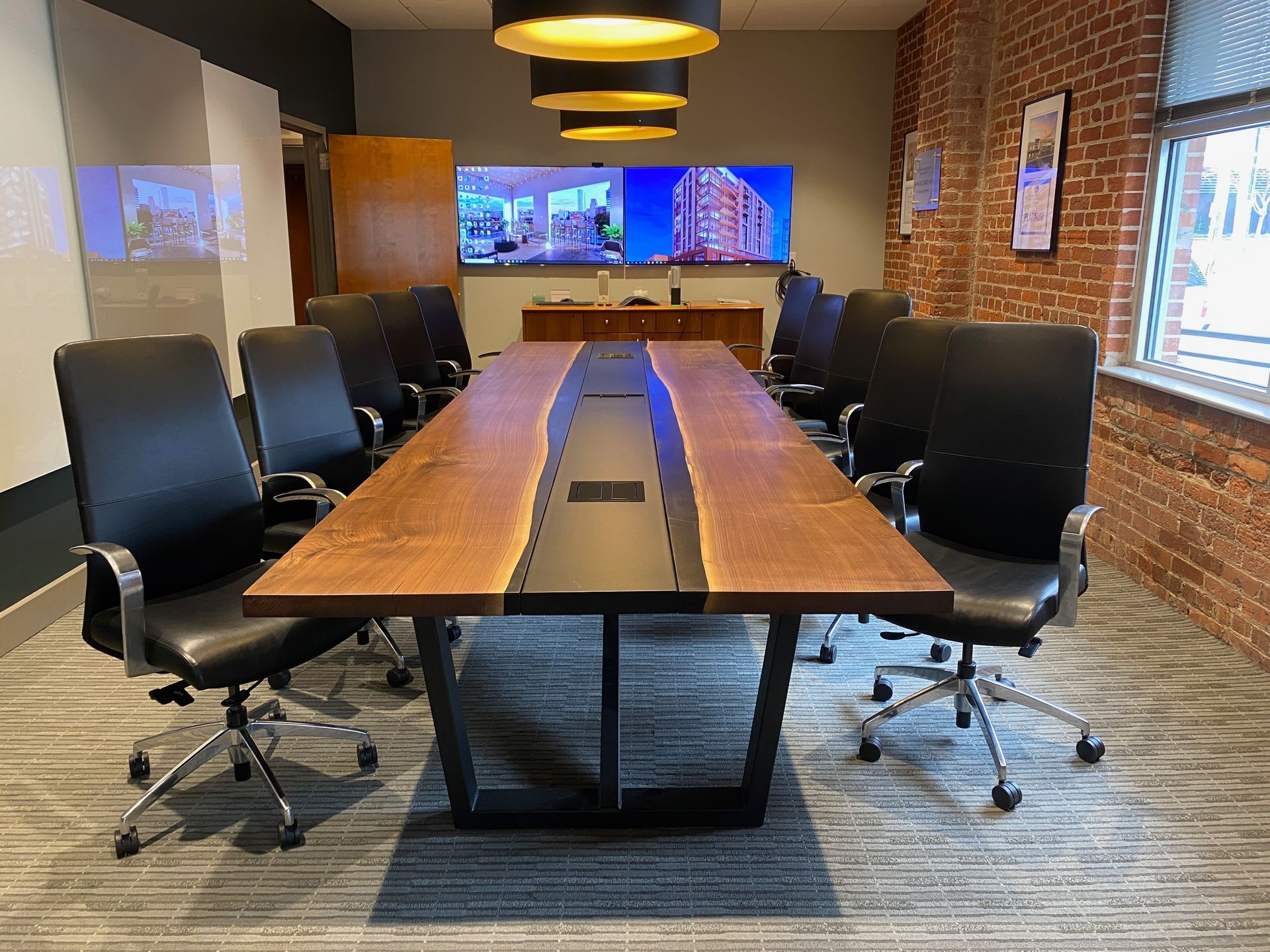 Conference room with long wooden table, black chairs, and large screen.