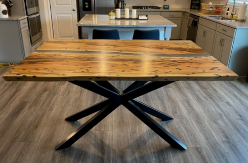 A wooden table with a black metal base is sitting in a kitchen.