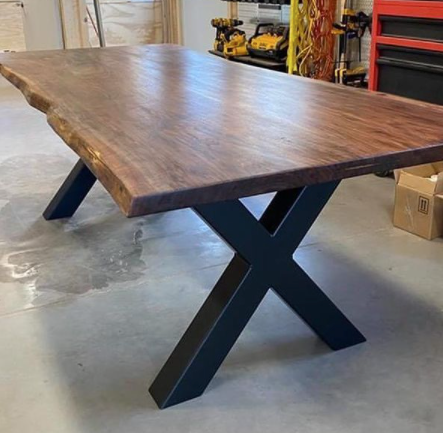 A wooden table with black metal legs is sitting in a garage.