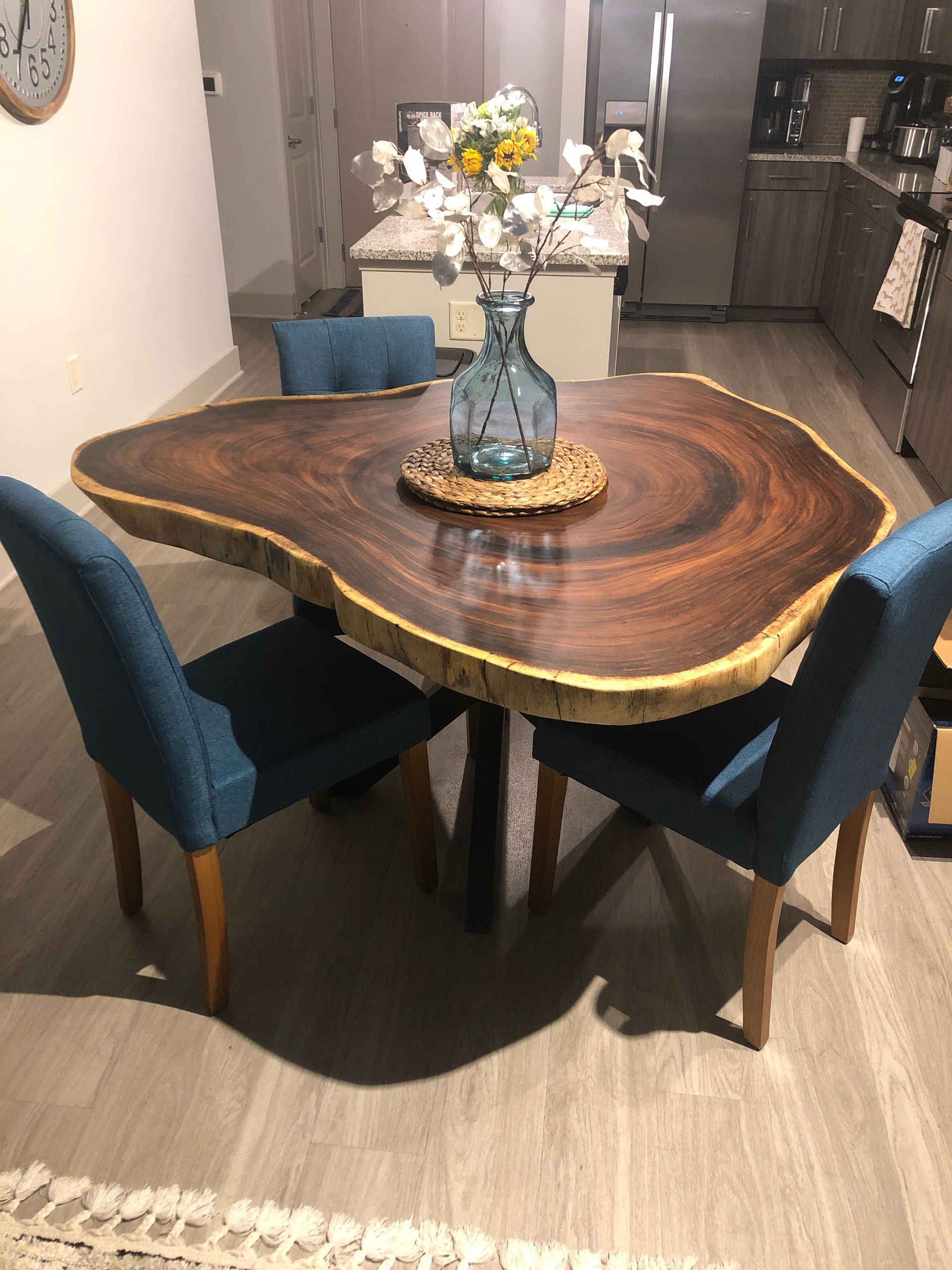 A wooden table with a vase of flowers on it in a kitchen.