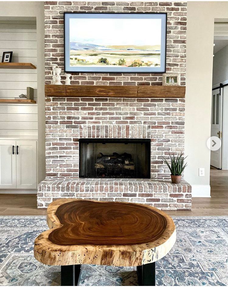 A living room with a brick fireplace and a wooden coffee table.