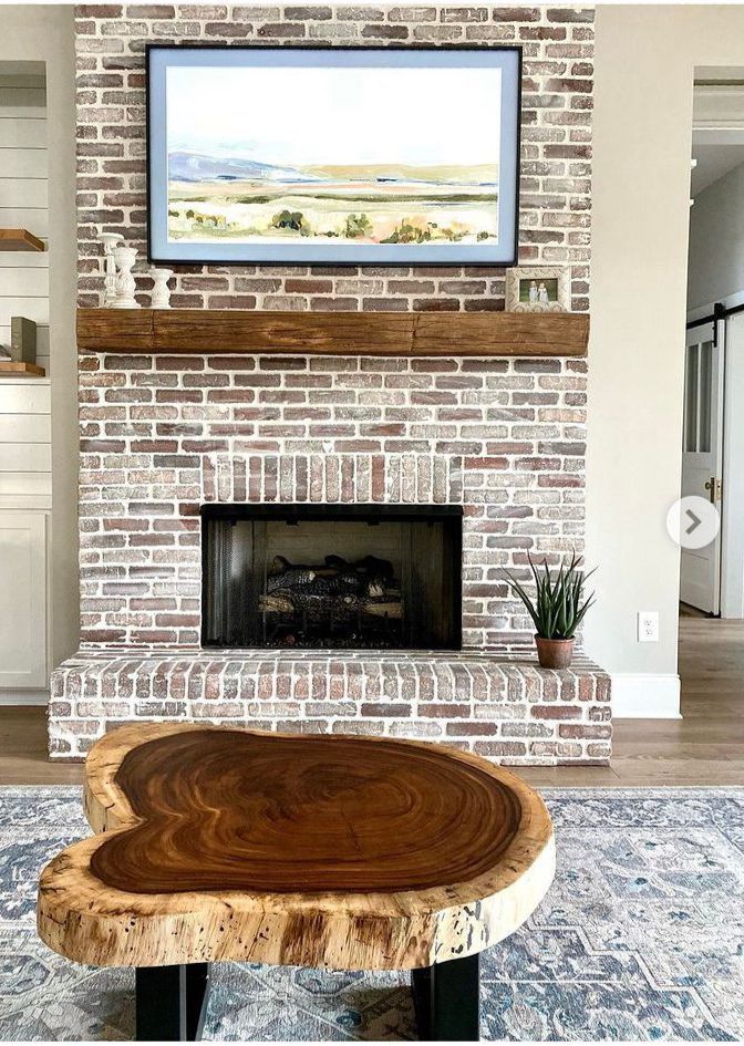 A living room with a brick fireplace and a wooden coffee table.