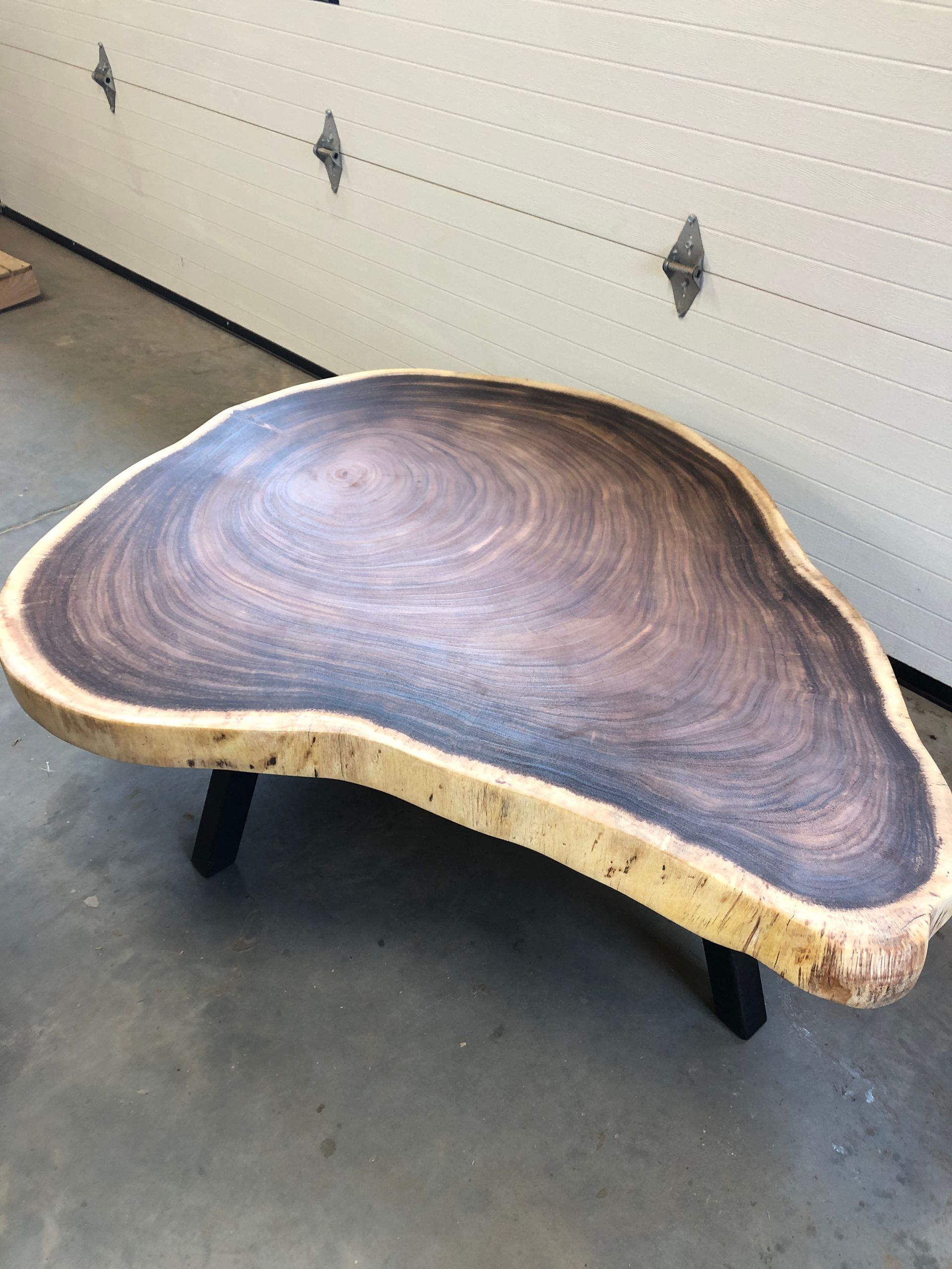 A large piece of wood is sitting in front of a garage door.