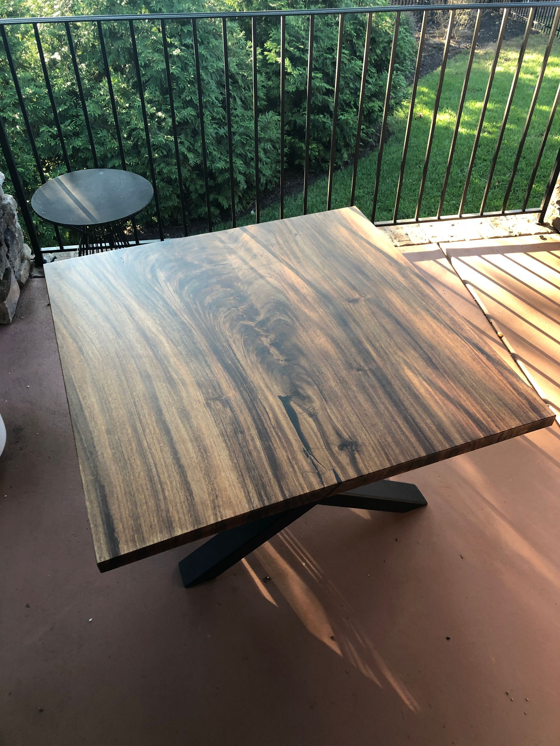 A wooden table is sitting on a balcony next to a railing.