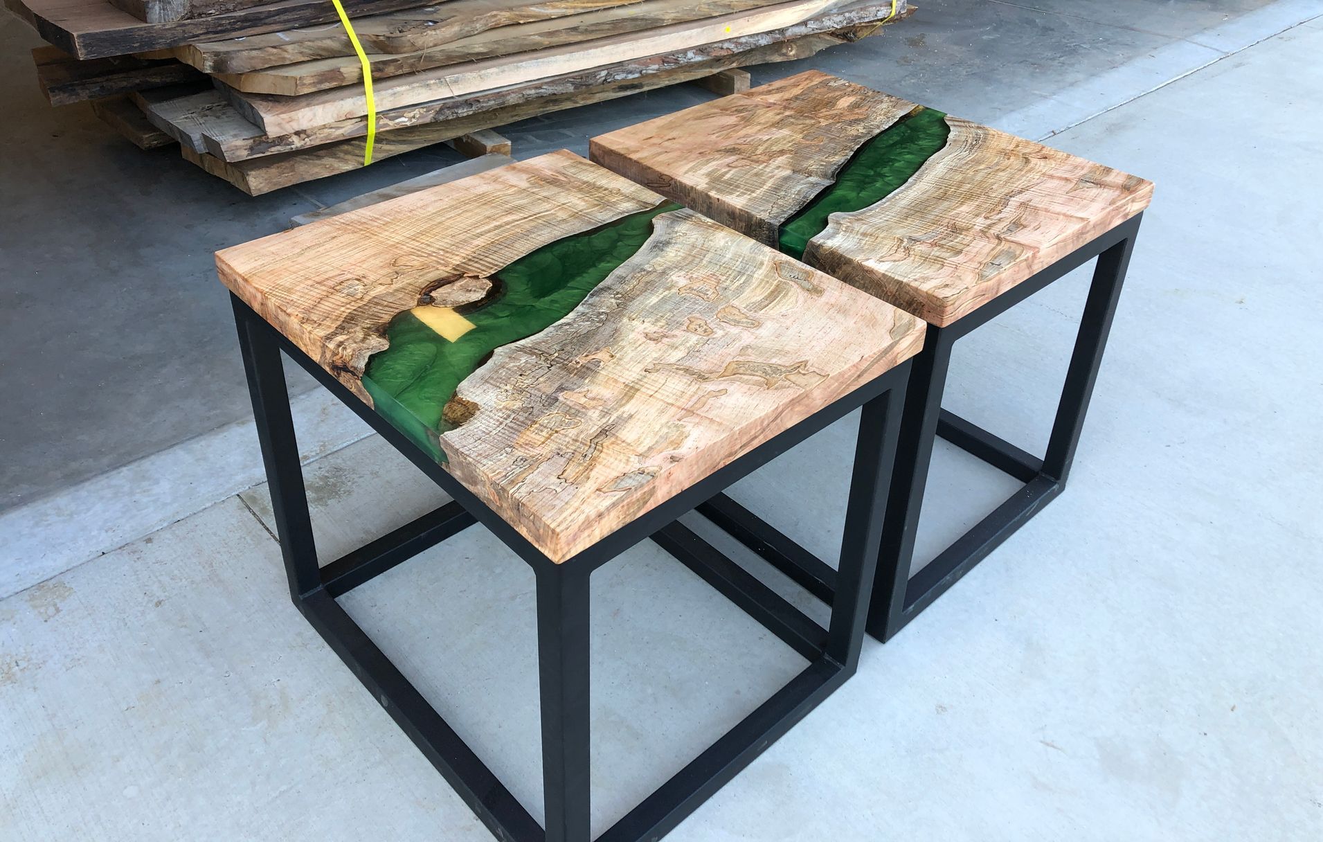 Two tables made of wood and resin are sitting next to each other on a concrete floor.