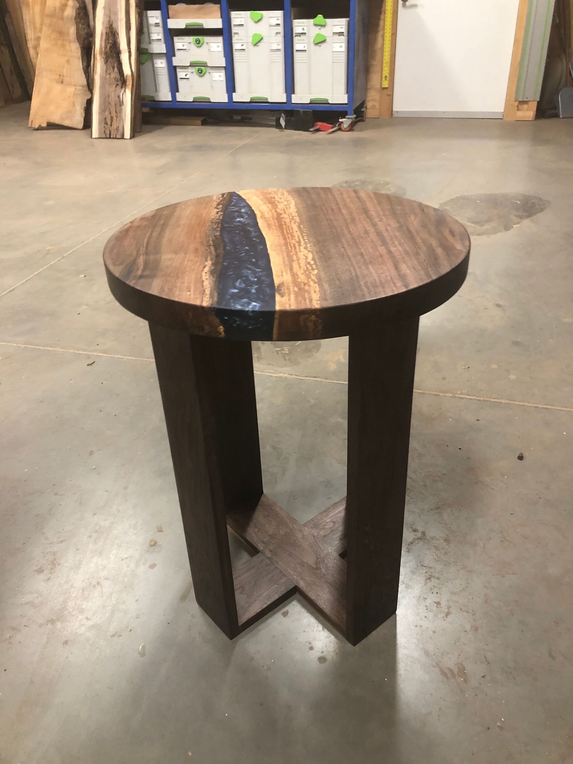 A round wooden table is sitting on a concrete floor.