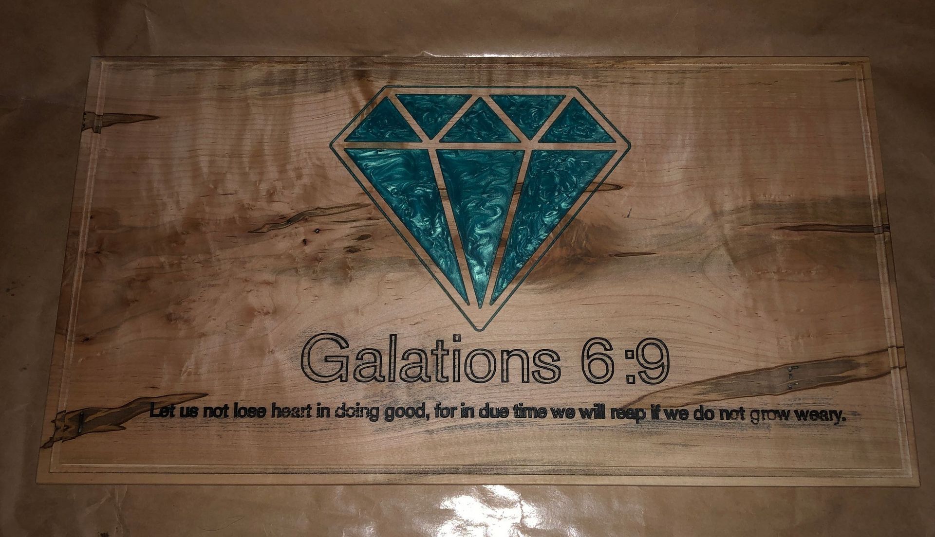 A wooden sign with a diamond and a bible verse on it.