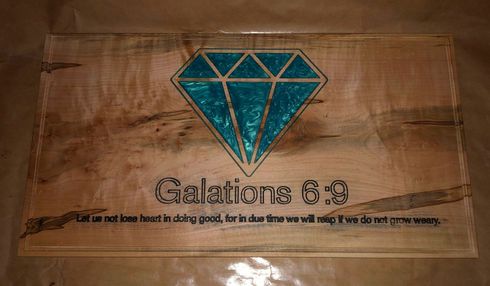 A wooden sign with a diamond and a bible verse on it