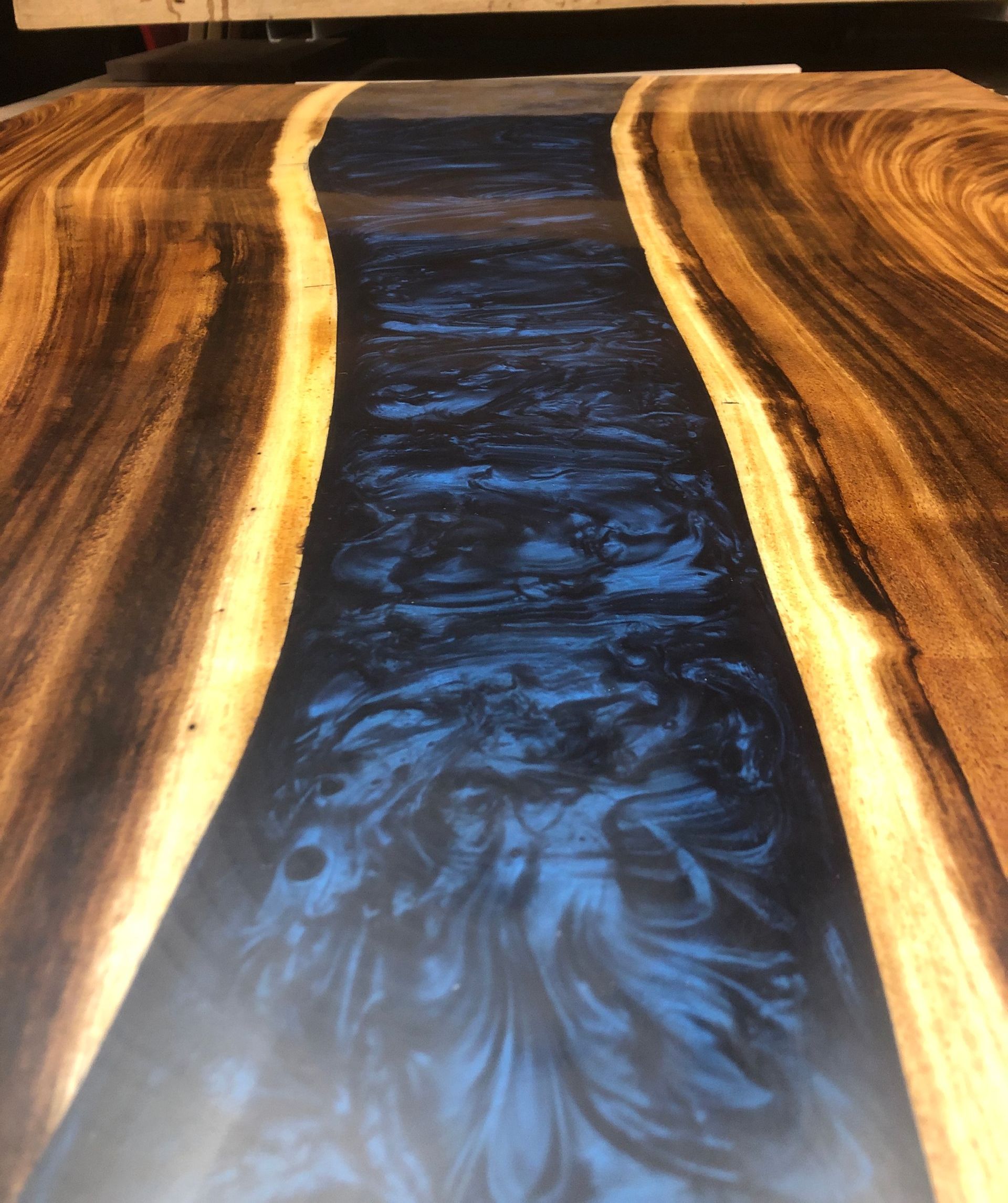 A wooden table with a epoxy river flowing through it.