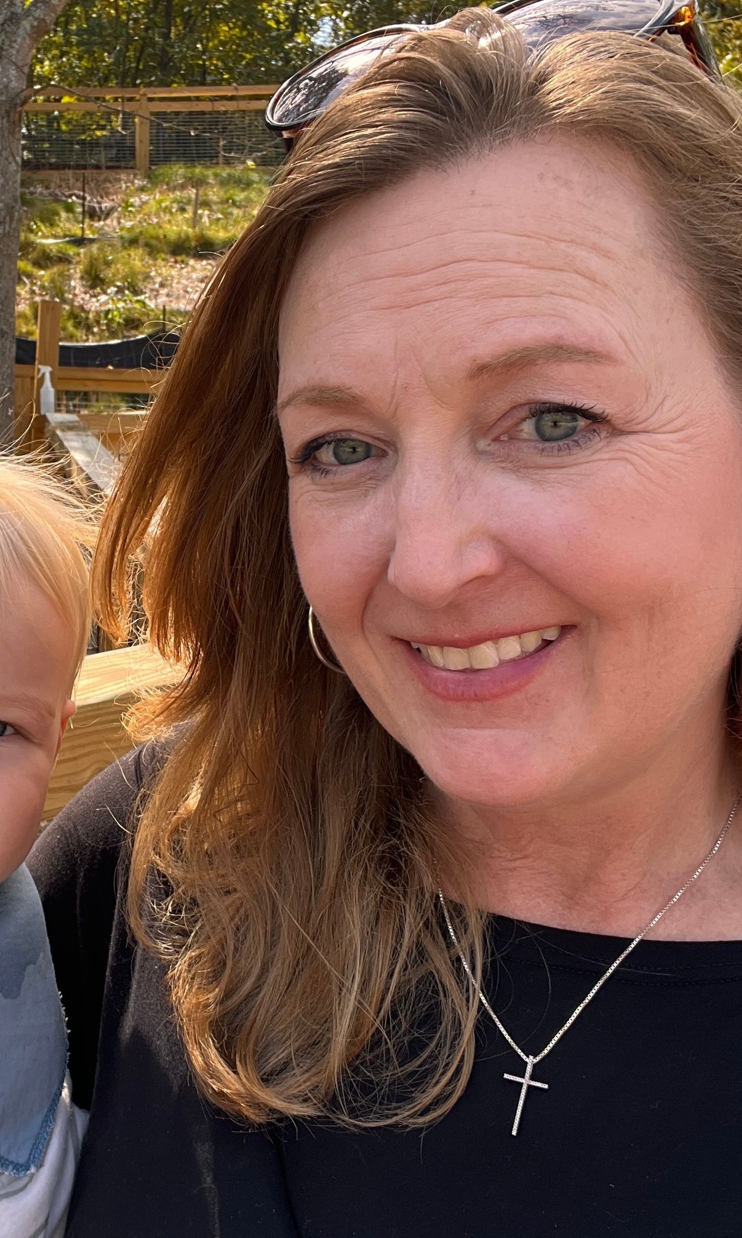 A man with a beard is wearing a blue plaid shirt and smiling.