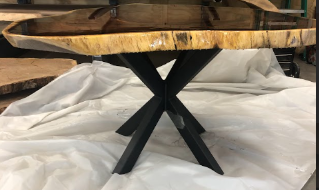 A wooden table with a metal base is sitting on a white cloth.