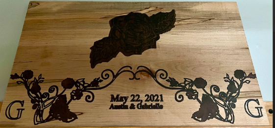 Wooden sign with etched design: island, floral accents, names, and date 