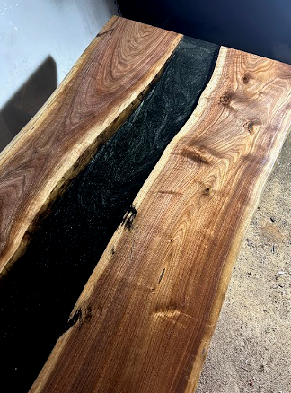 A wooden table with black metal legs is sitting in a garage.