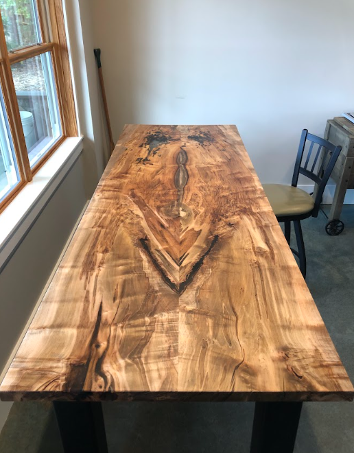 A wooden table is sitting in front of a window in a room.