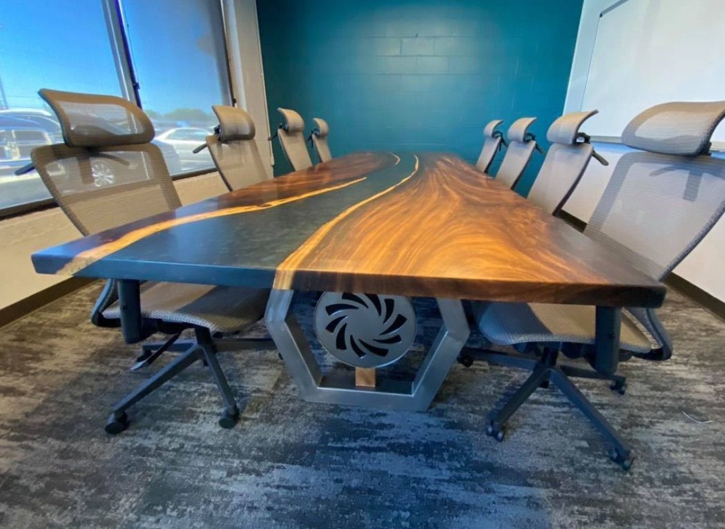 Conference room with a wooden table inlaid with epoxy. Chairs around the table. Teal wall.