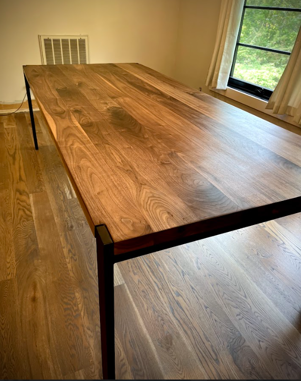 A wooden table with black metal legs is sitting in a garage.