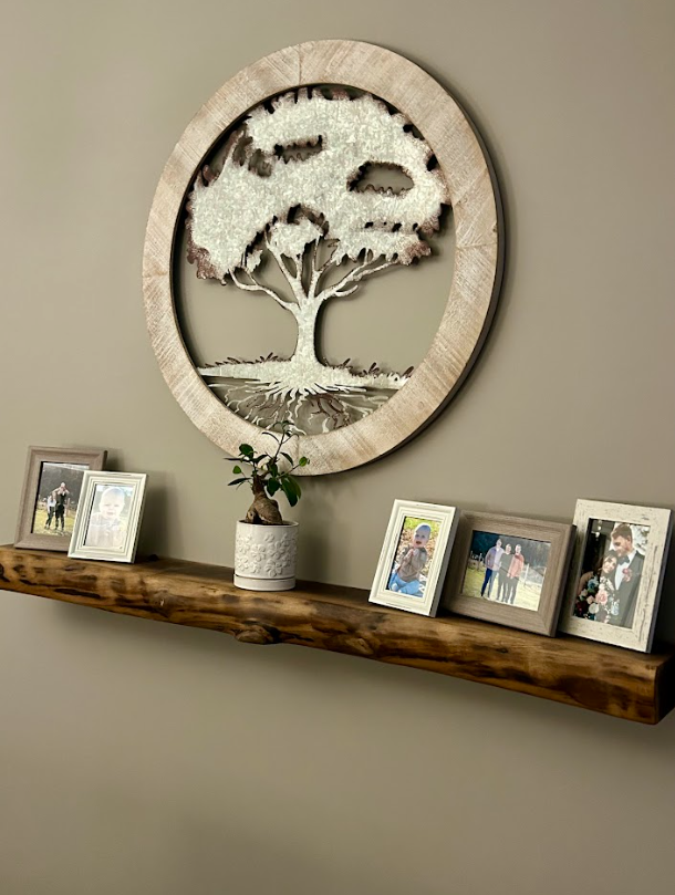 A wooden shelf with pictures and a tree on it.