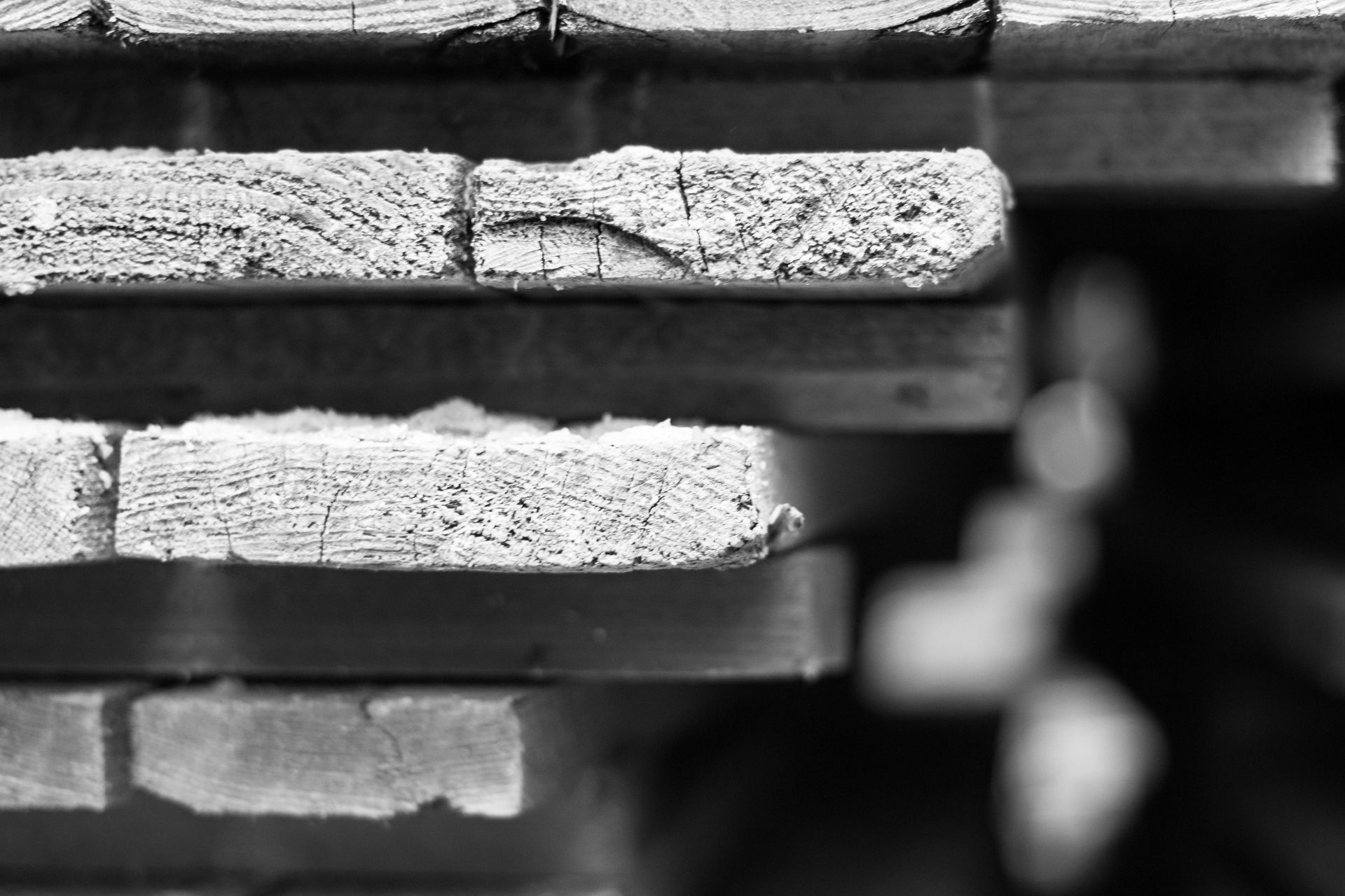 A black and white photo of a stack of wooden boards.