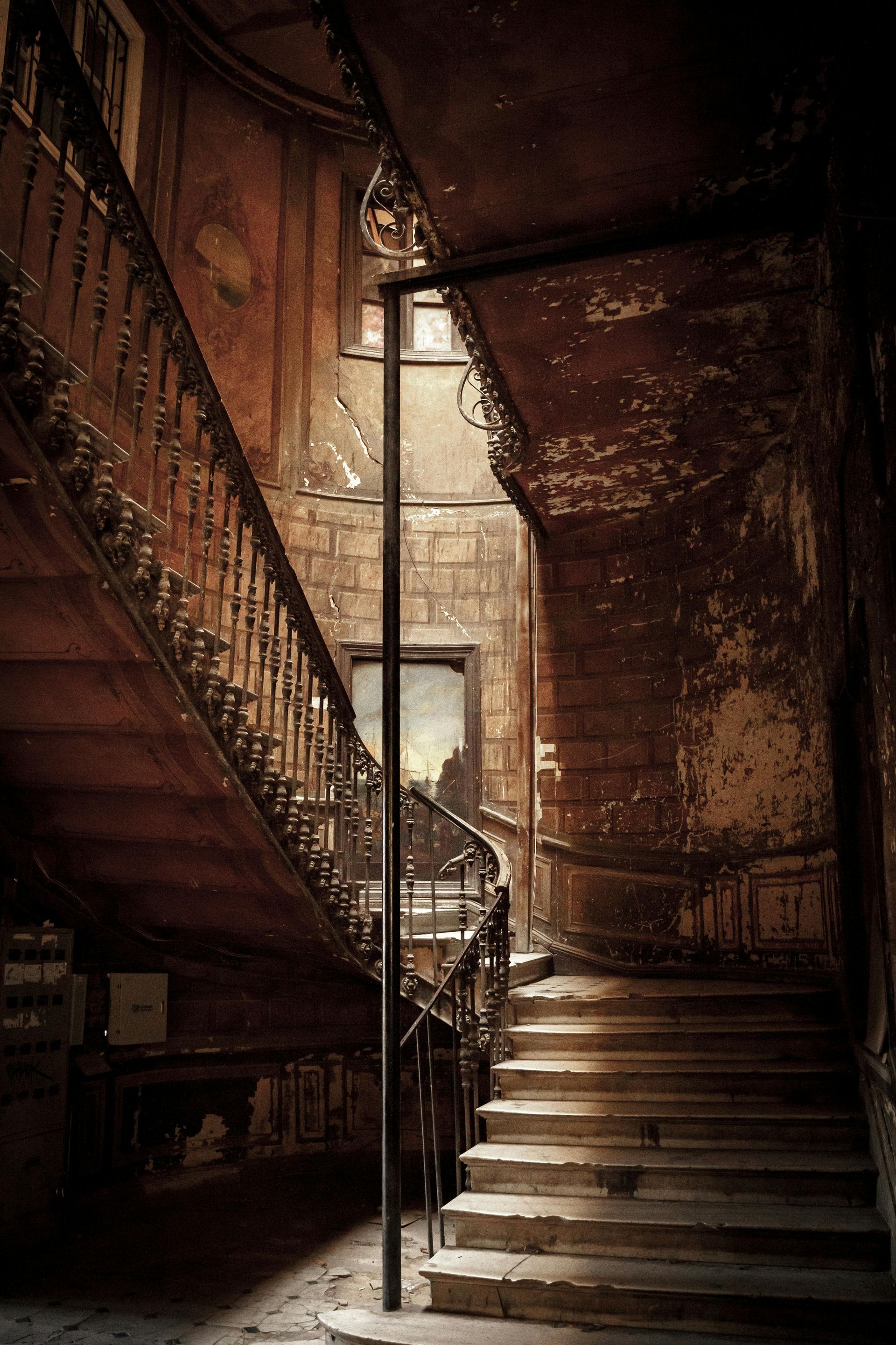 A staircase in an old building with a painting on the wall.