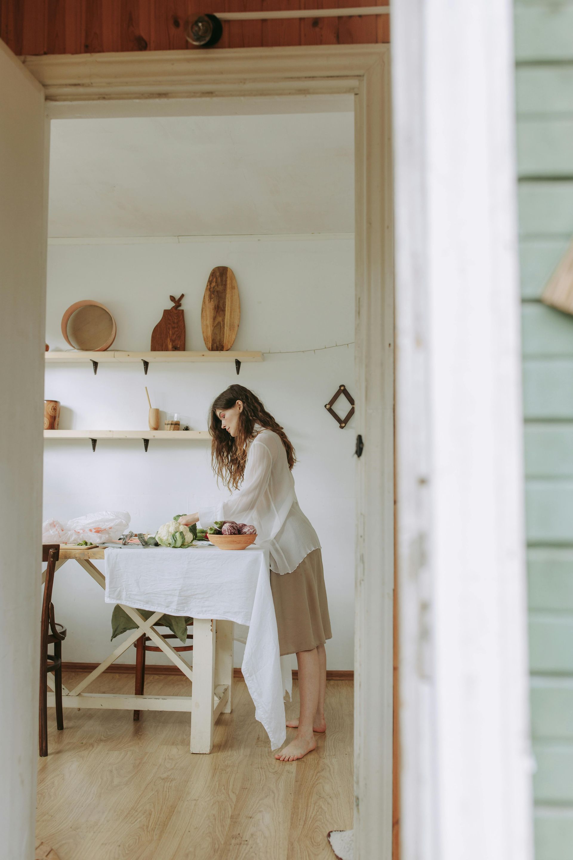 A woman is standing in front of a table with a white tablecloth.