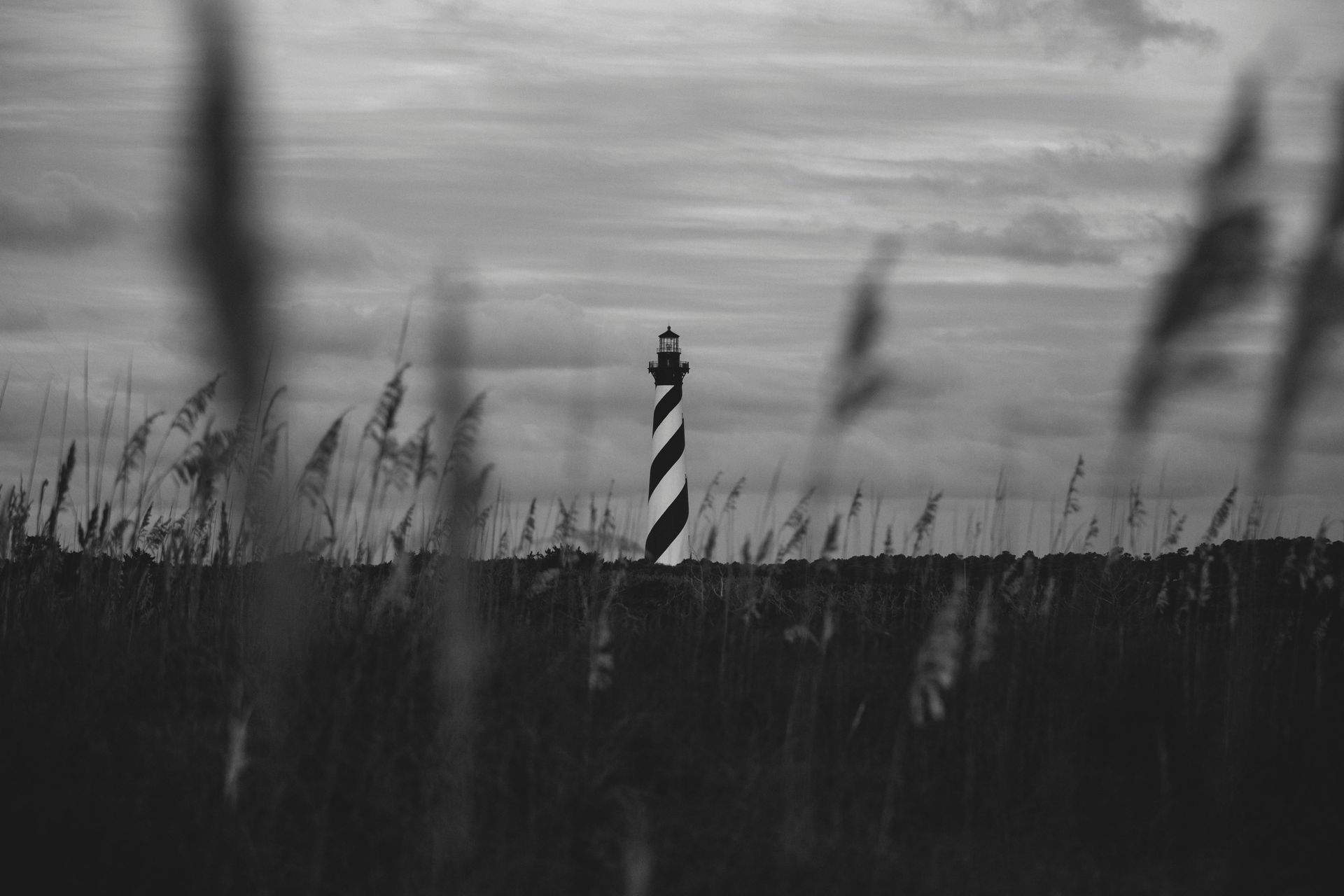 A black and white photo of a lighthouse in the middle of a field.