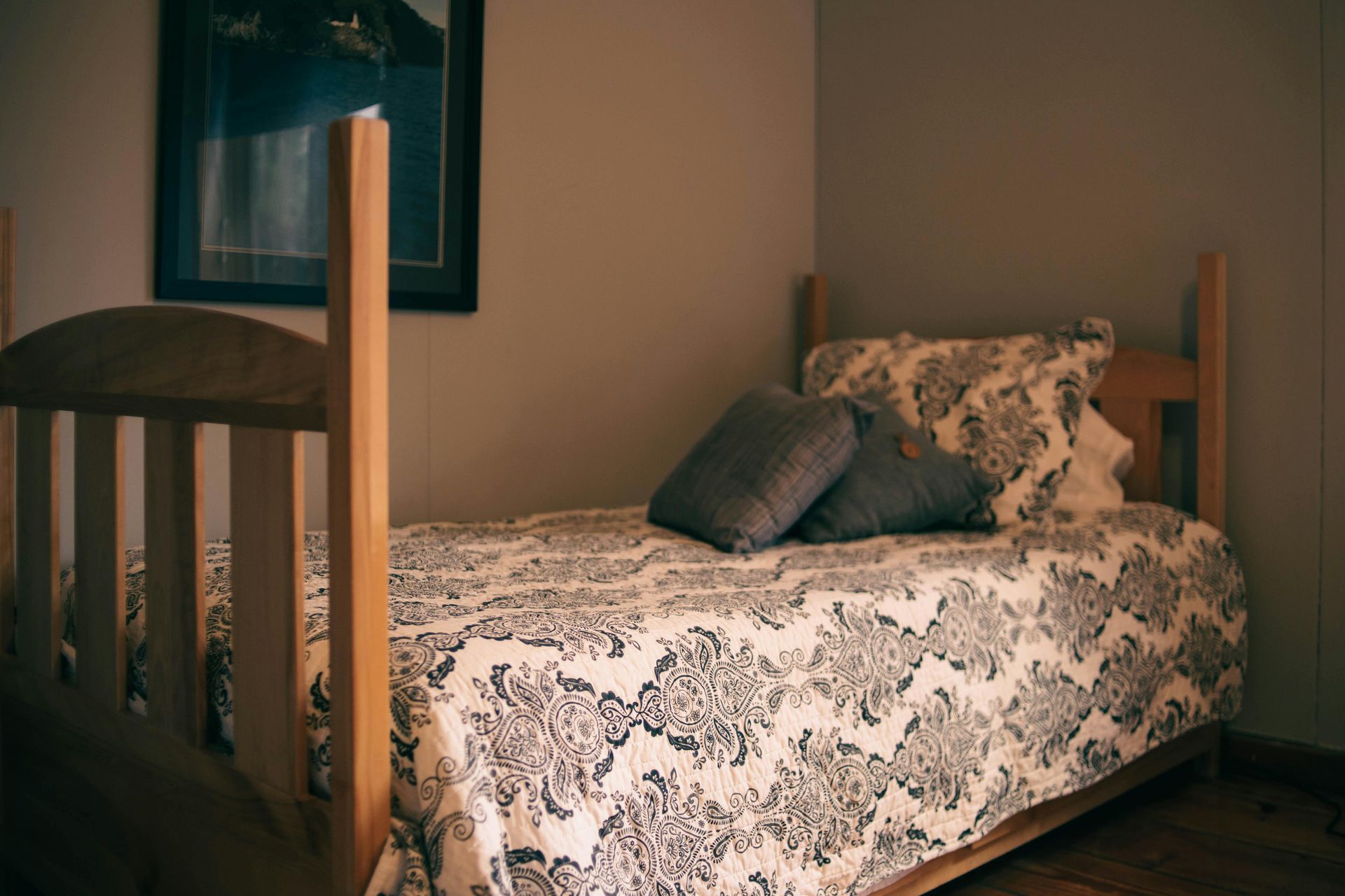 Twin bed in a room with a picture on the wall. Black and white patterned bedding.
