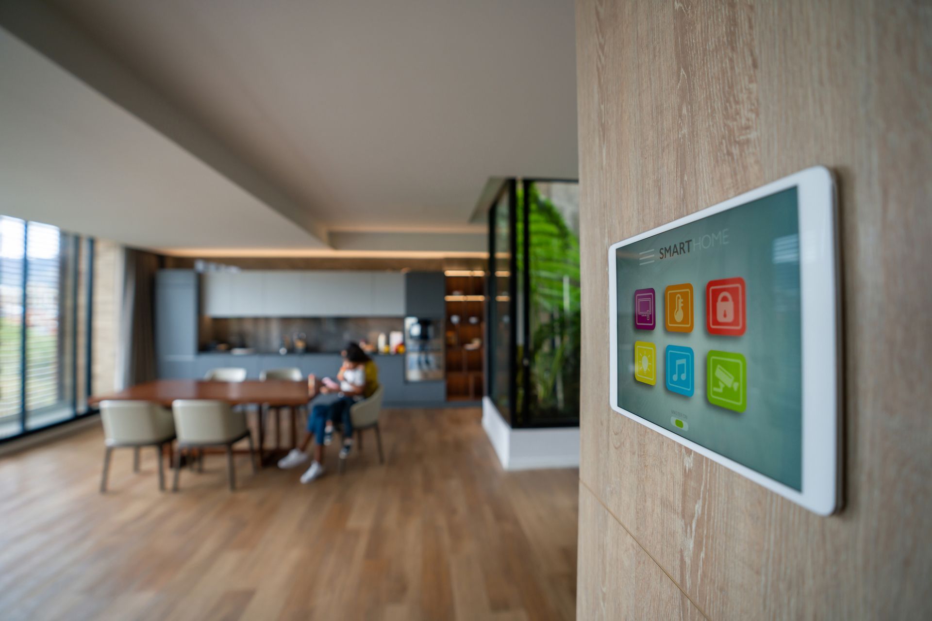 Una donna è seduta a un tavolo in un soggiorno con un tablet sul muro.